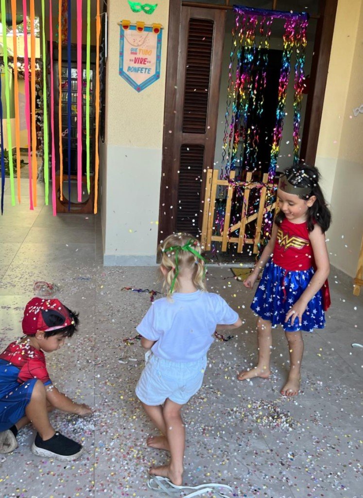 Crianças fantasiadas brincando com confete em festa de aniversário no Novo Brincar