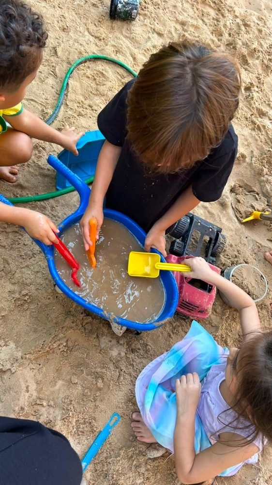 Crianças em atividade sensorial com água, parte da exploração do corpo na Sala Broto